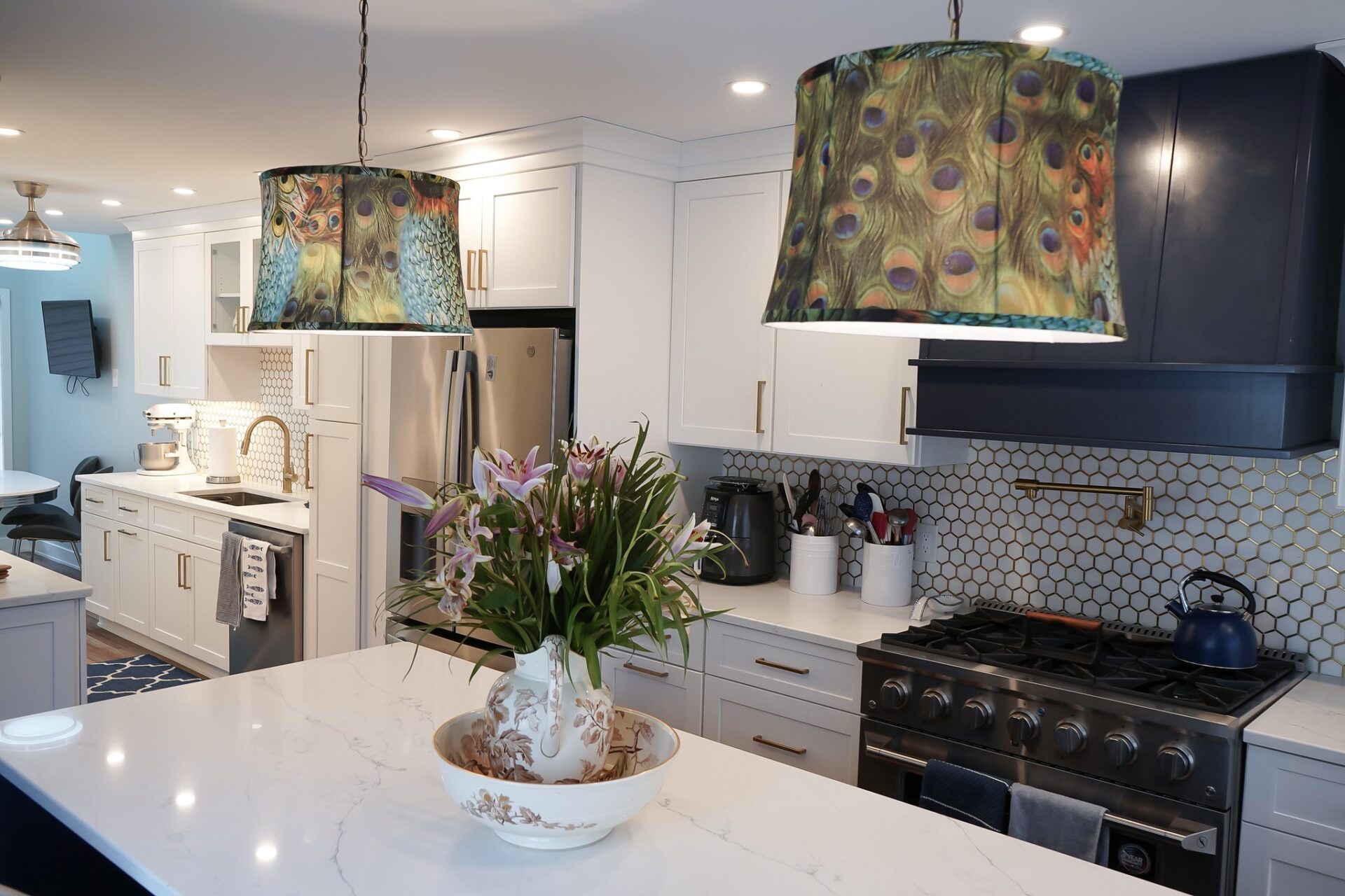Kitchen with counters berlin Modern kitchen remodel featuring white shaker cabinets, stainless steel appliances, marble countertops, floral centerpiece, and colorful peacock feather pendant lights — Central Connecticut Building and Remodeling, Berlin, CT.